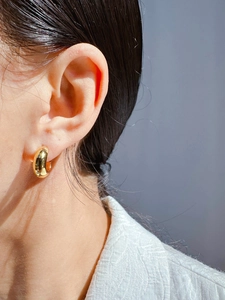 Close-up of gold-plated thick C-shaped hoop earrings worn by a model for daily wear