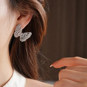 Close-up of model wearing a silver butterfly stud earring with micro-set zircons
