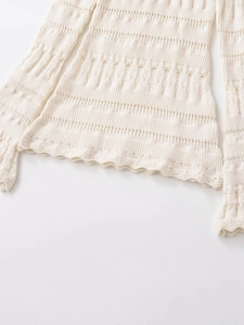 Close-up of cream crochet knit sweater with scalloped edges and pointelle hollow details