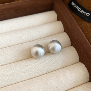 Close-up of silver round stud earrings with a brushed matte texture on velvet display