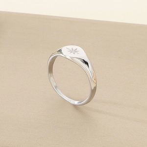 Detailed view of silver signet ring with engraved star pattern on a polished oval surface