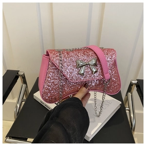 Pink sequin bag featuring a silver bow accent and chain strap on a black chair