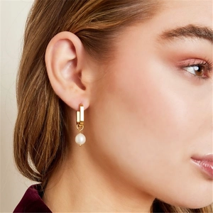 Close-up of elegant U-shaped gold pearl earrings on model showing glossy 8mm white pearls