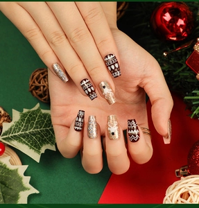 Detail of red Christmas press-on nails with elk patterns and gold glitter accents