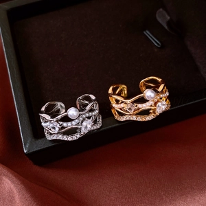 Détail de bagues superposées en or et argent avec perles et cristaux marquise