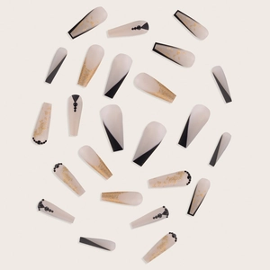 Detailed view of matte nude coffin press-on nails with black geometry and gold foil accents