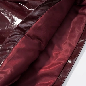 Dettaglio del cappotto in pelle verniciata bordeaux con fodera in raso e cuciture di pregio