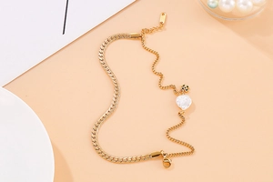 Detail of golden double-layer shell bracelet with pearl on elegant ceramic plate