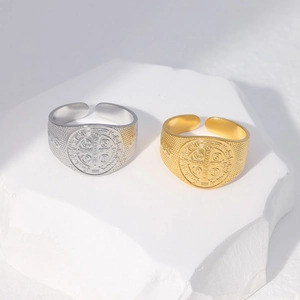 Detailed view of Saint Benedict medal rings with relief textures on white stone base