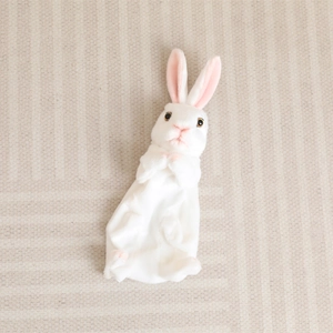Plush white long-eared rabbit toy with soft fur and pink inner ears on a beige rug