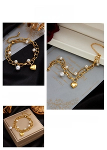 Detail view of dual-layer gold chain bracelet with pearl beads and heart pendant charm