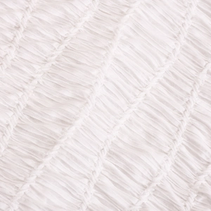 Close-up of white summer dress fabric showing textured smocked detail and pleated finish