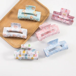 Easter bunny and floral hair claws in pastel candy colors on a wooden tray