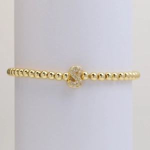 Close-up of golden beaded stretch bracelet with a micro-paved zircon letter S pendant