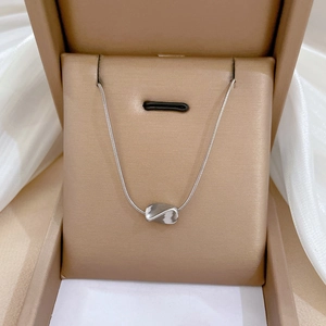 Macro shot of silver wave rectangle pendant on a fine snake chain in a jewelry box