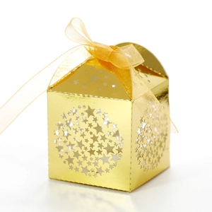 Detail of laser-cut gold gift box with star patterns and a matching organza ribbon bow