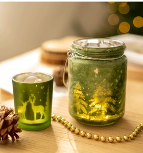 Détail de bougeoirs de Noël en verre givré vert avec silhouette de cerf sur bois