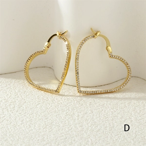 Close-up of golden hollow heart earrings with shimmering zircon stones and high-shine finish