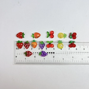 Flat lay of resin fruit nail charms showing size measurement with a ruler scale