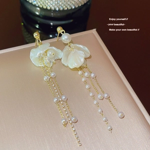 Elegant gold-tone tassel earrings featuring pearls and white petal charms on a luxury box