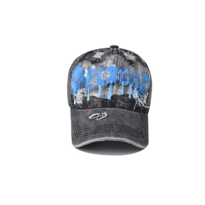 Close-up of distressed acid wash denim texture and blue graffiti print on baseball cap