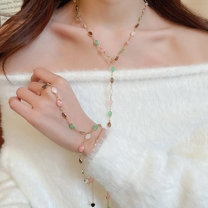 Close-up of golden Y-necklace and bracelet set with colorful resin stones on a model