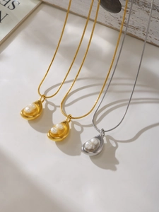Detail of elegant gold and silver snake chain necklaces with irregular pearl pendants