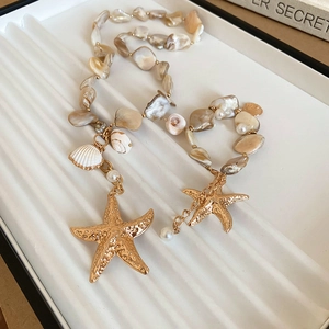 Detail showing irregular champagne beads with large gold starfish pendants on a necklace