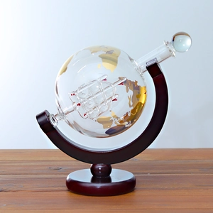 Detail of world map globe decanter with ship inside and wooden stand on a table