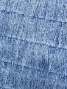 Close-up of light blue tassel fabric with metallic luster and layered fringe details