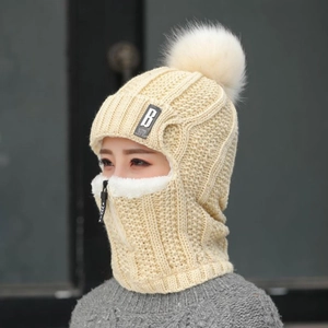 Détail d'une cagoule tricotée crème avec fermeture éclair et pompon en peluche