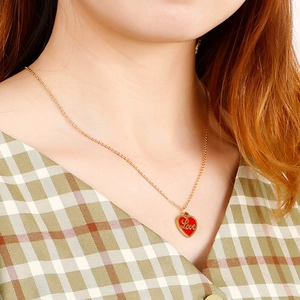 Élégant collier en acier inoxydable doré avec pendentif cœur rouge Love sur un mannequin