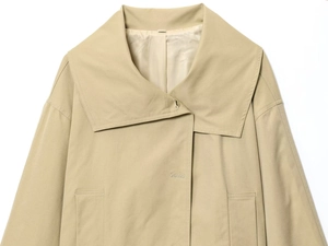 Dettaglio del trench kaki che mostra i ampi revers e la trama del tessuto in twill di cotone