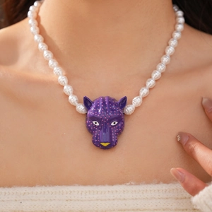 Gros plan exquis d'un collier pendentif tête de panthère violette avec perles baroques