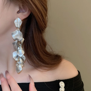Macro side view of long matte silver layered petal tassel earrings on a model