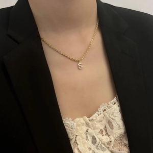 Gros plan du collier en acier titane doré avec pendentif lettre S serti de oxydes de zirconium