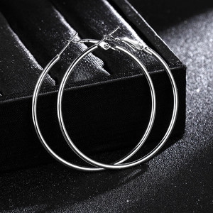 Macro view of polished silver metal hoop earrings resting on a black jewelry box