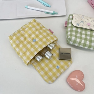 Detail shot of yellow gingham quilted storage pouch holding various cosmetic samples