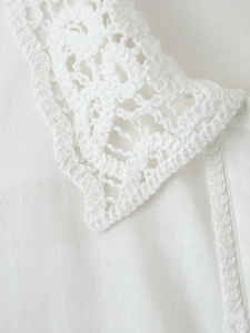 Détail du col en dentelle au crochet et du tissu texturé sur une chemise blanche femme