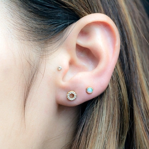 Detail of s925 silver stud earrings with gold round zircon and opal stones on ear