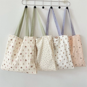 Detail of five quilted tote bags with bear and floral prints on a metal rack