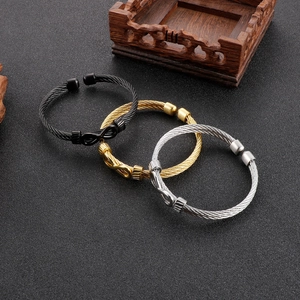 Three-color infinity cable wire bracelets in black, gold and silver on grey surface