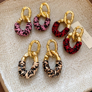 Detail view of vintage gold chain link earrings set with leopard and texture fabric wrap