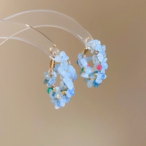Macro detail of handmade beaded earrings with blue natural stones and colorful accents