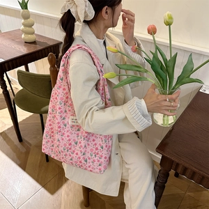 Close-up of pink tulip quilted tote bag with floral patterns and a side woven label