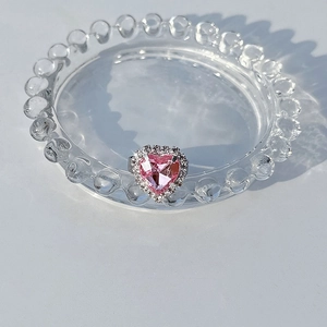 Detailed close-up of a silver heart ring with pink gemstone and halo diamond settings