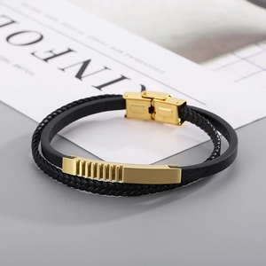 Detail of men's double-layer black leather bracelet with gold textured metal clasp