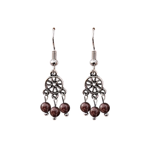 Macro detail of silver dreamcatcher earrings with deep red garnet beads in boho style