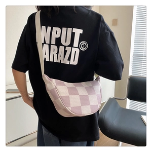 Detail of purple and white checkerboard knit crescent bag on a model shoulder
