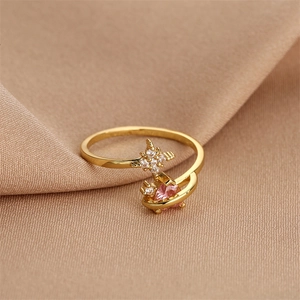 Macro shot of gold-plated ring with pink heart zircon and star accents on silk fabric
